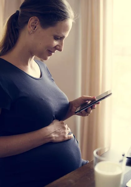 一个开朗的孕妇使用电话 — 图库照片