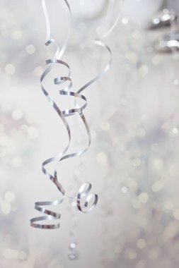 Arka planda gümüş kıvrımlı ince folyolar ve bokeh. Kutlama konsepti