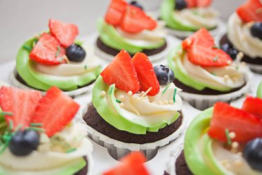 Kekleri beyaz ve yeşil kremalı, çilekli ve böğürtlenli bir kutuya koy.