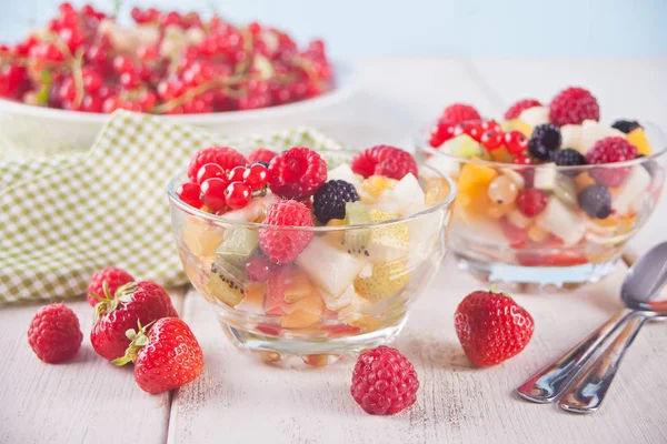 Салат зі свіжими фруктами та ягодами на мисках на білому тлі . — стокове фото