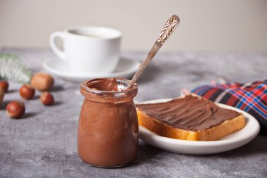 Çikolata kremalı tost, beton arka planda bir fincan kahve.