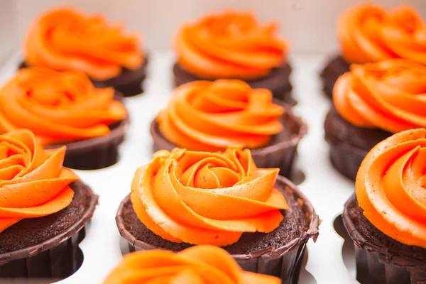 Cerrar cupcakes de chocolate con crema de naranja en una caja de papel para regalo —  Fotos de Stock