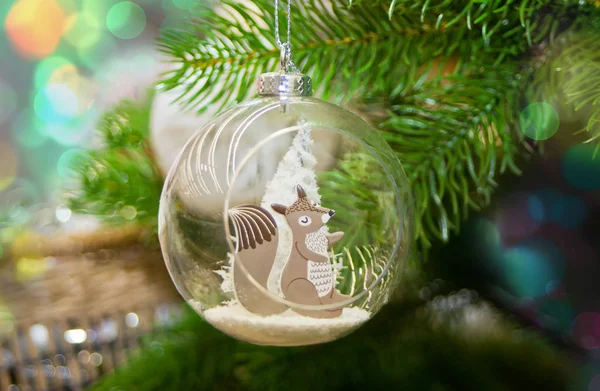 Decorated Christmas tree and hanging small ball with funny squirrel toy inside — Stock Photo, Image