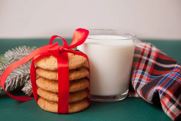 Copo de leite, biscoitos e ramo de pinho na mesa verde — Fotografia de Stock