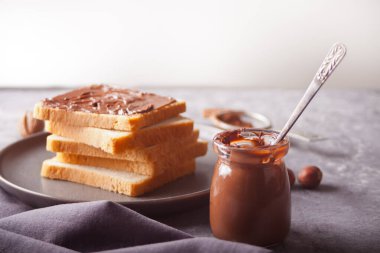 Çikolata kremalı tost, beton arka planda bir kavanoz çikolata kreması.