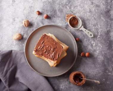 Çikolata kremalı tost, beton arka planda bir kavanoz çikolata kreması.