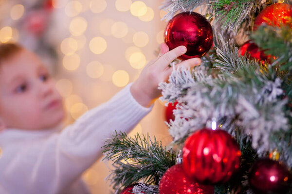Boy in a white sweater decorated Christmas tree.