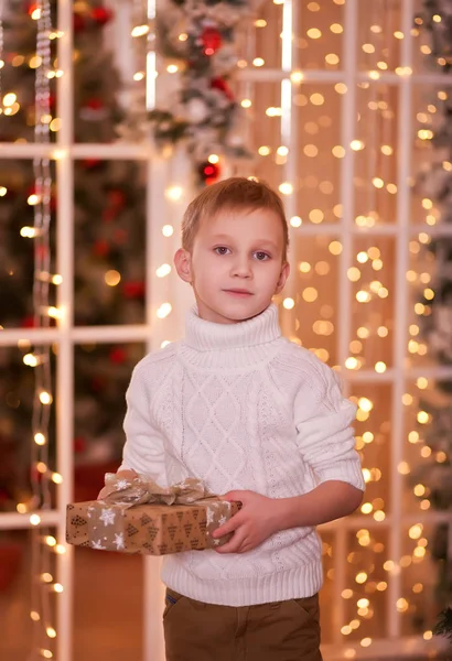 Dziecko w białym swetrze z dzianiny trzymając pudełko prezentów świątecznych w rękach — Zdjęcie stockowe