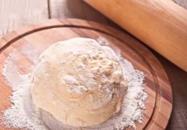 Siyah arka planda ahşap kesme tahtasında pizza veya ekmek pişirme için ham hamur