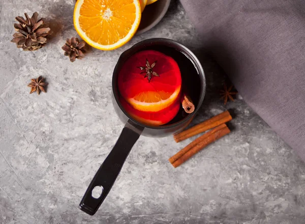 Old metal pan pot of tasty mulled wine with pot with spices and orange fruits on wooden table. Top view. — Stock Photo, Image