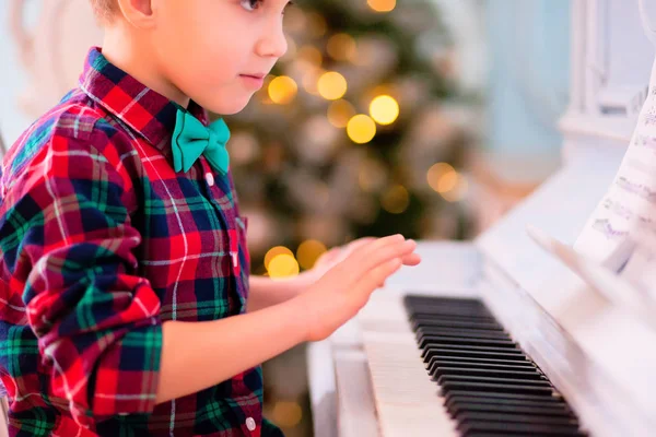 Chłopiec w koszuli w kratkę i motyl grający na pianinie. Koncepcja świąteczna. — Zdjęcie stockowe