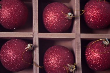 Ahşap bir kutuda kırmızı Noel parıldayan topları.