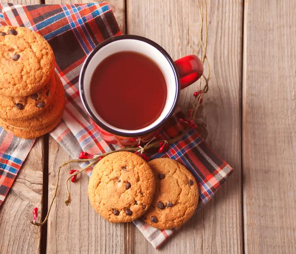 Galletas con taza roja de té caliente o café en la mesa de madera — Foto de Stock