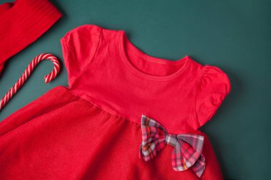 Kırmızı elbise, kareli yay, tayt, yeşil arka planda şeker kamışı. Kızlar için Noel partisi modası.