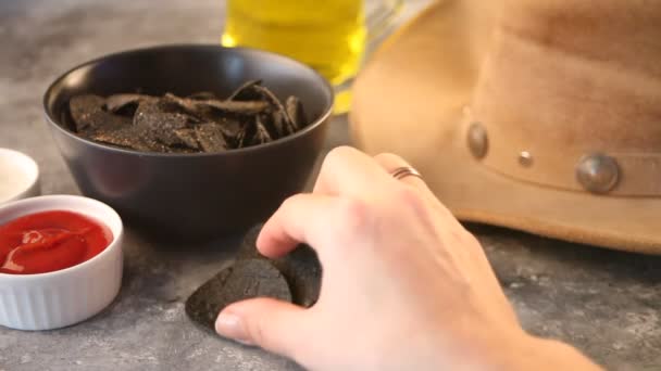 Mano de mujer toma nachos de patatas fritas mexicanas negras y se sumerge en una salsa de pausa . — Vídeos de Stock