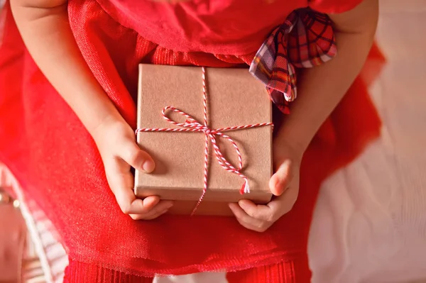 Niña en vestido rojo sosteniendo una caja de regalo de Navidad en una mano — Foto de Stock
