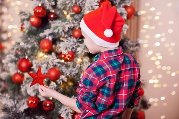 Ręka chłopca trzymając świąteczny wystrój duża czerwona gwiazda w rękach na tle choinki — Zdjęcie stockowe