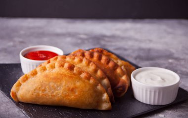 Köfteli börek, börek ve siyah tabakta sos..