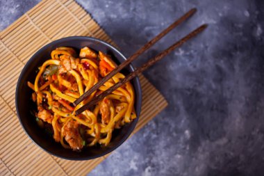 Udon eriştesi ve kase içinde tavuk eti, koyu taştan arka planda. Uzayı kopyala Üst görünüm.