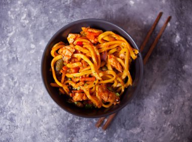 Udon eriştesi ve kase içinde tavuk eti, koyu taştan arka planda. Uzayı kopyala Üst görünüm.