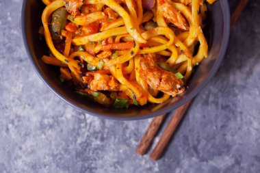 Udon eriştesi ve kase içinde tavuk eti, koyu taştan arka planda. Üst Manzara. Kapat.