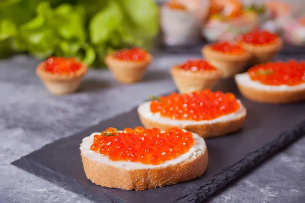 Caviar vermelho fresco no pão no prato preto. Sanduíches com caviar vermelho . — Fotografia de Stock