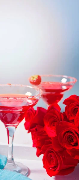 澄んだガラスの赤いエキゾチックなアルコールカクテルとロマンチックなディナーのための木製の白いトレイの赤いバラ. — ストック写真
