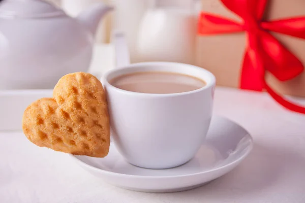 Taza de café y una galleta en forma de corazón con caja de regalo en la mesa blanca — Foto de Stock