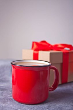 Red mug of coffee, gift box on the gray table