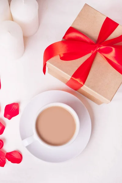 Cup of coffee, gift box and rose petals on the white table — Stock Photo, Image