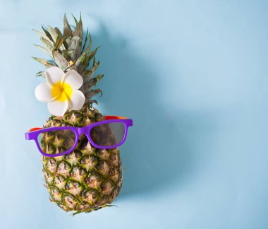 Mavi arka planda güneş gözlüklü sulu ananas