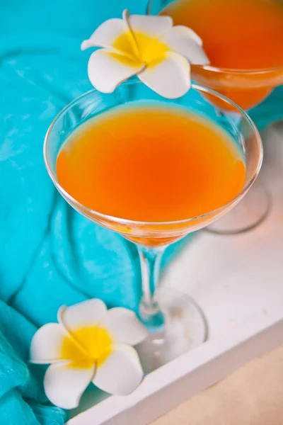 一杯热带异国情调的多果果汁鸡尾酒，放在白盘上，配上水仙花。 三地海滩野餐概念. — 图库照片