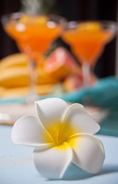 Plumeria frangipani flower and glasses of tropical exotic multifruit juice cocktail drink on the background. Tripical beach picnic concept. — 스톡 사진