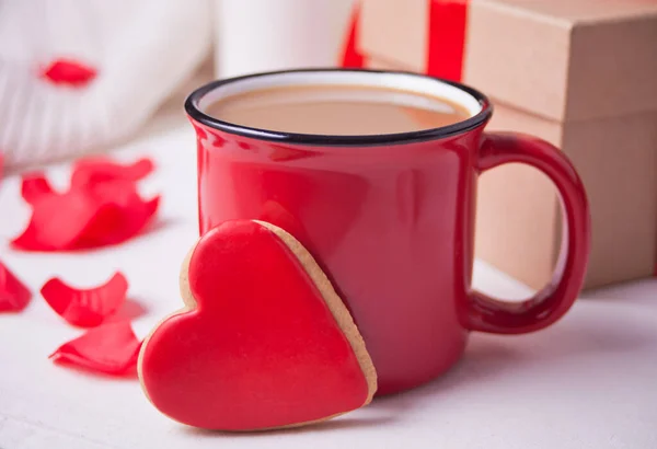 Caneca vermelha de café, caixa de presente e pétalas de rosa vermelha na mesa branca — Fotografia de Stock