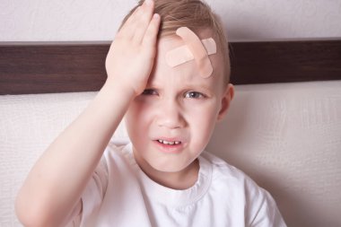 Little boy with plaster on head and doesn t feel well. clipart