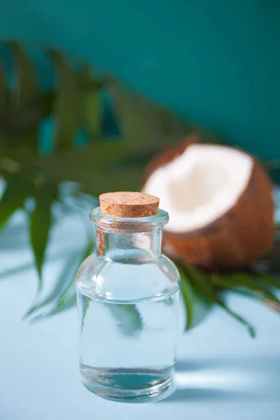 Óleo de coco em garrafa com coco, flor Plumeria frangipani e folha de palmeira verde. Alimentos saudáveis, conceito de cuidados com a pele . — Fotografia de Stock