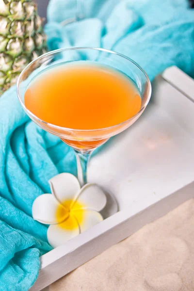 トロピカルエキゾチックなマルチフルーツジュースカクテルのグラスは、プルメリアフランジパニの花と白いトレイで飲みます。体験型ビーチピクニックのコンセプト. — ストック写真