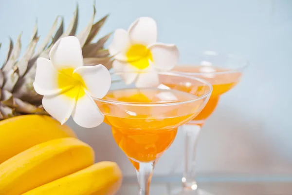 Glasses of tropical exotic multifruit juice cocktail drink with plumeria frangipani flower. Troical beach picnic concept. — 스톡 사진