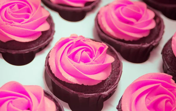 Cerrar cupcakes de chocolate con crema violeta lila en una caja de papel para regalo . — Foto de Stock