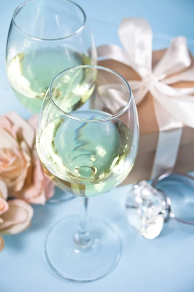 Dos copas con vino de uva blanca con rosas y caja de regalo en el fondo. Concepto de cena romántica . — Foto de Stock