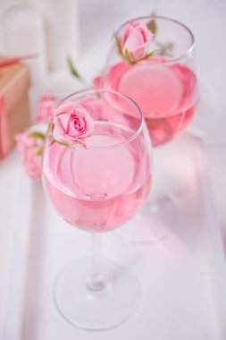 İki bardak pembe üzümlü şarap ve gül çiçekleri. Romantik yemek konsepti.