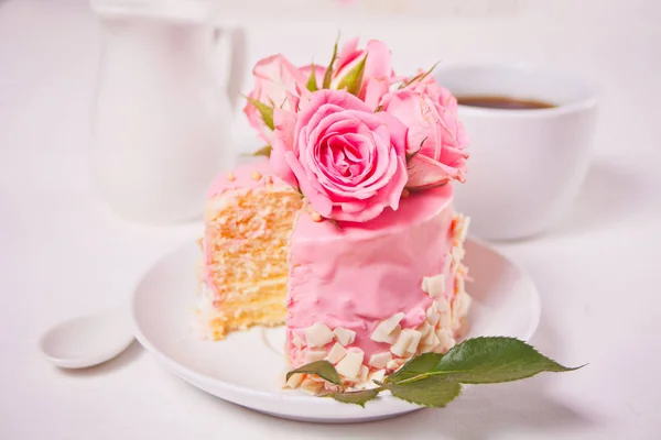 Mini pequeño pastel con esmalte rosa, hermosas rosas, taza de café en la mesa blanca . — Foto de Stock