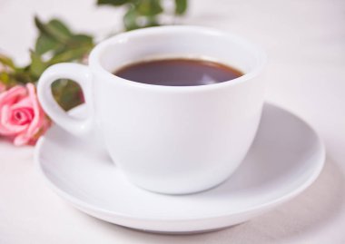 Beyaz masada bir fincan çay ve pembe güller