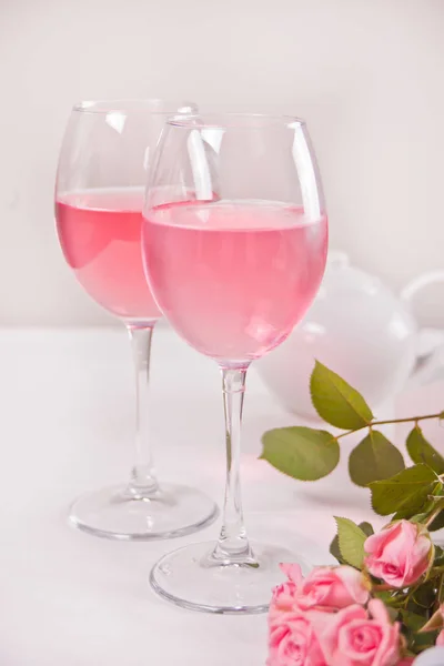 Två glas med rosa druvvin med rosenblommor. Romantiskt middagskoncept. — Stockfoto