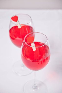 Beyaz arka planda kırmızı iğneli kırmızı şarap kadehleri.