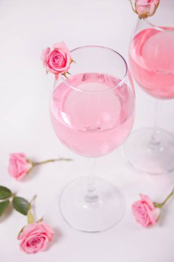 İki bardak pembe üzümlü şarap ve gül çiçekleri. Romantik yemek konsepti.