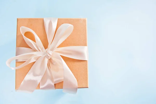 Caja de regalo con lazo beige sobre fondo azul. Vista superior. Copiar espacio — Foto de Stock