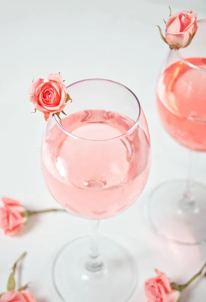 Dois copos com vinho de uva rosa com flores de rosas. Conceito de jantar romântico . — Fotografia de Stock