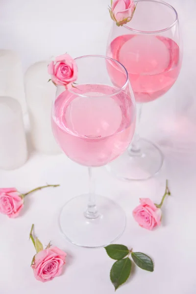 Dois copos com vinho de uva rosa com flores de rosas. Conceito de jantar romântico . — Fotografia de Stock