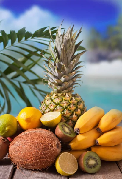Frutas tropicais orgânicas na mesa de madeira sob folha de palma . — Fotografia de Stock